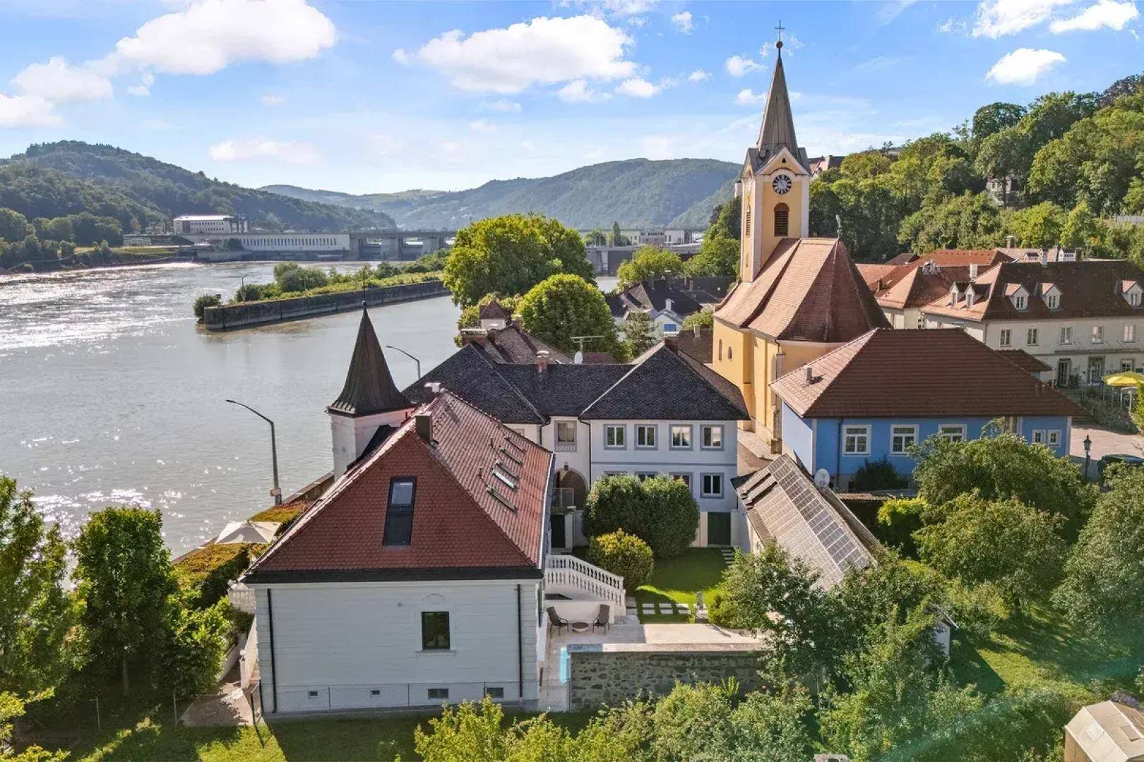 Malerische Luftaufnahme des Anwesens mit Kirche und Flusslandschaft im Hintergrund.