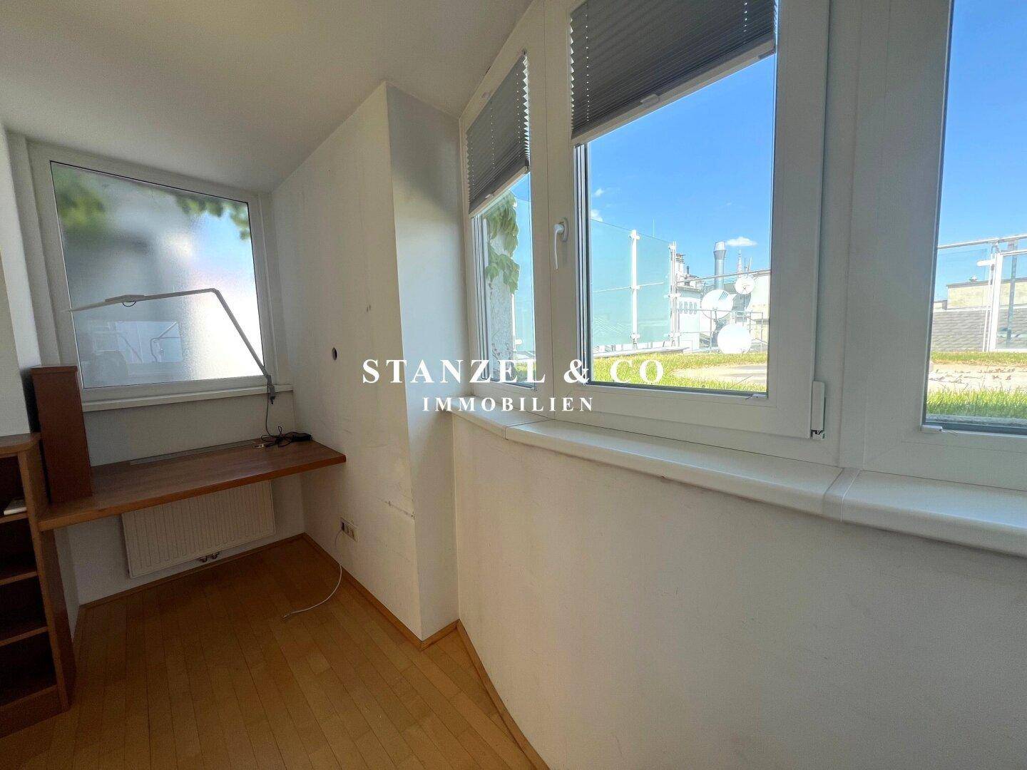 Helles Zimmer mit Holzboden und großen Fenstern, ideal als Arbeitszimmer oder kleines Schlafzimmer.
