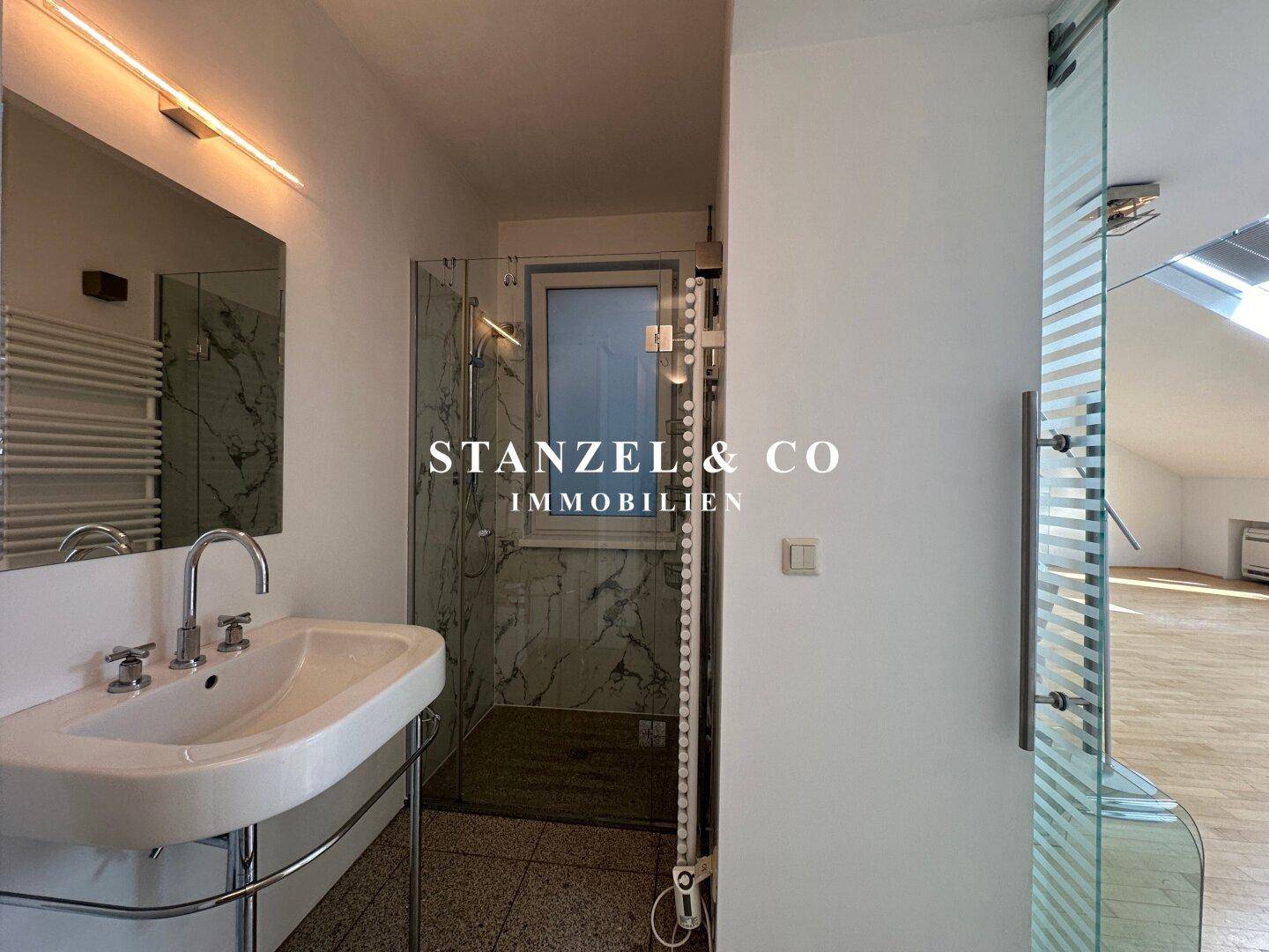 Modernes Badezimmer mit Waschbecken, Spiegel, beheiztem Handtuchhalter und Duschkabine.