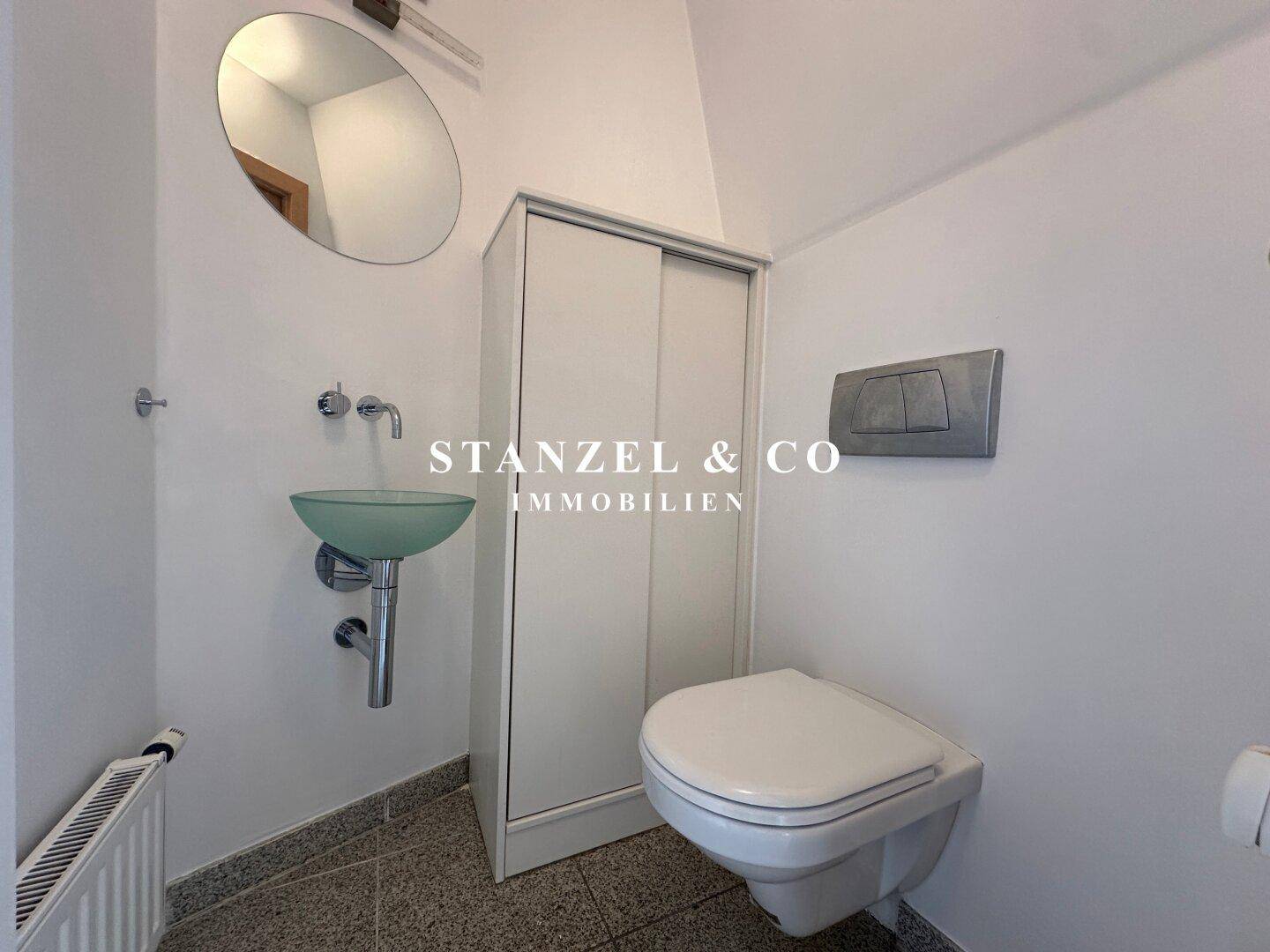 Separates Gäste-WC mit wandhängender Toilette und kleinem Waschbecken.
