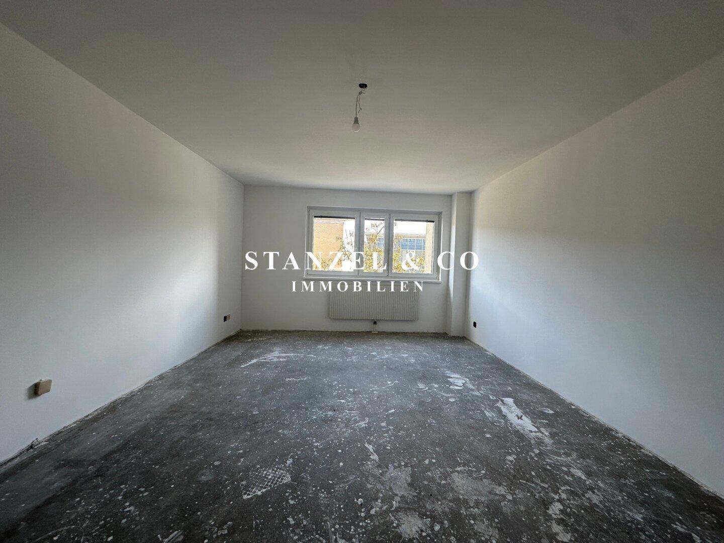 Heller, leerer Raum mit Fenster und Heizkörper, ideal für individuelle Einrichtung.