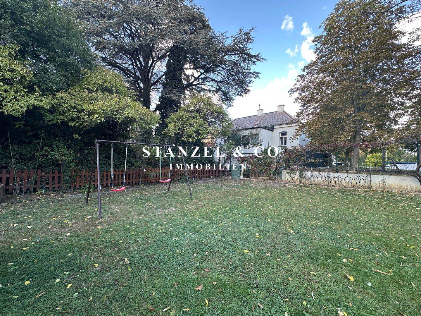 Weitläufiger Garten mit Rasenfläche, Schaukel und altem Baumbestand, perfekt für Familien.