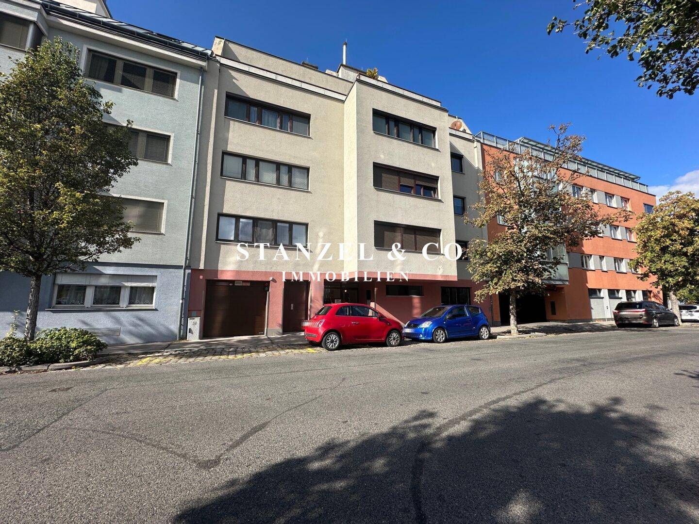 Straßenansicht eines Mehrfamilienhauses mit geparkten Autos, zeigt die moderne Architektur.