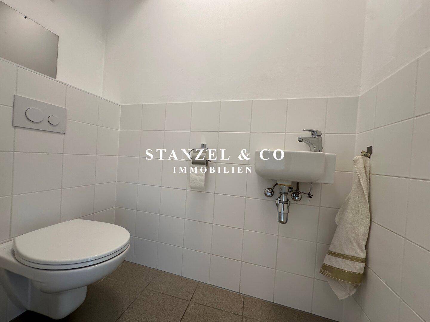 Kleines Gäste-WC mit Wand-WC und Handwaschbecken, hell gefliest und funktional.