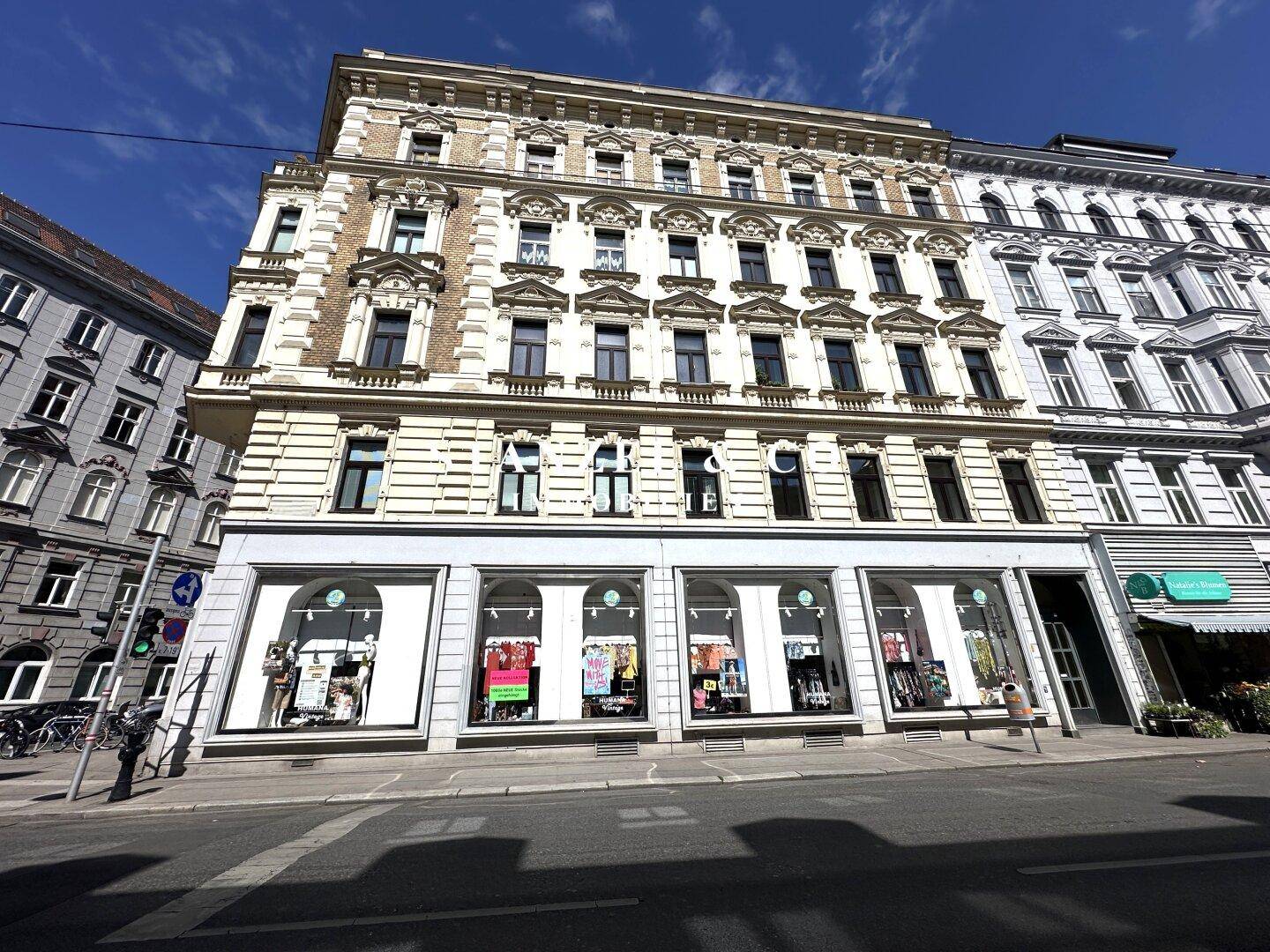 Breite Ansicht eines historischen Gebäudes mit großen Schaufenstern und klassischer Architektur in der Stadt.