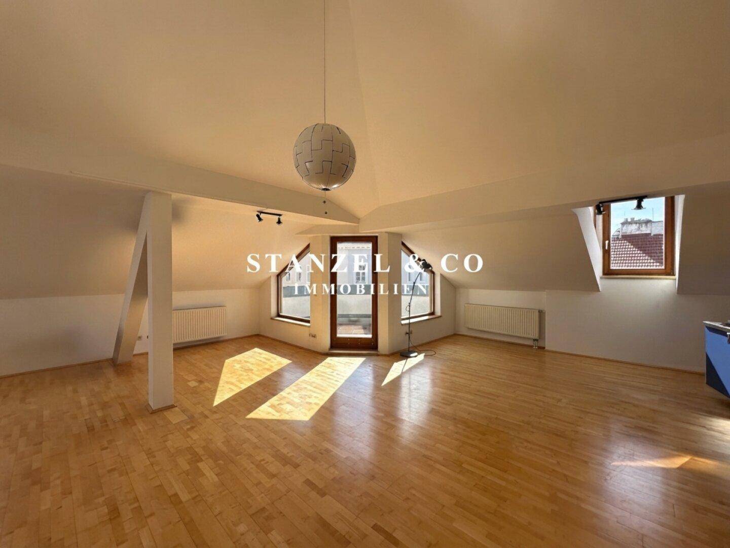 Geräumiges Dachgeschoss-Wohnzimmer mit Holzboden, Dachfenstern und viel natürlichem Licht.