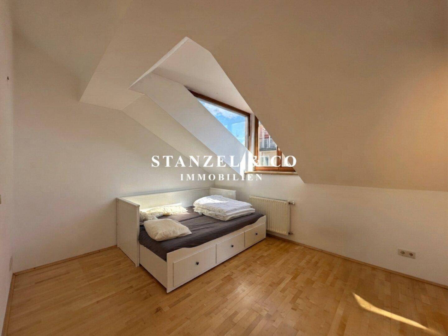 Schlafzimmer im Dachgeschoss mit Einzelbett, Holzboden und Dachfenster.