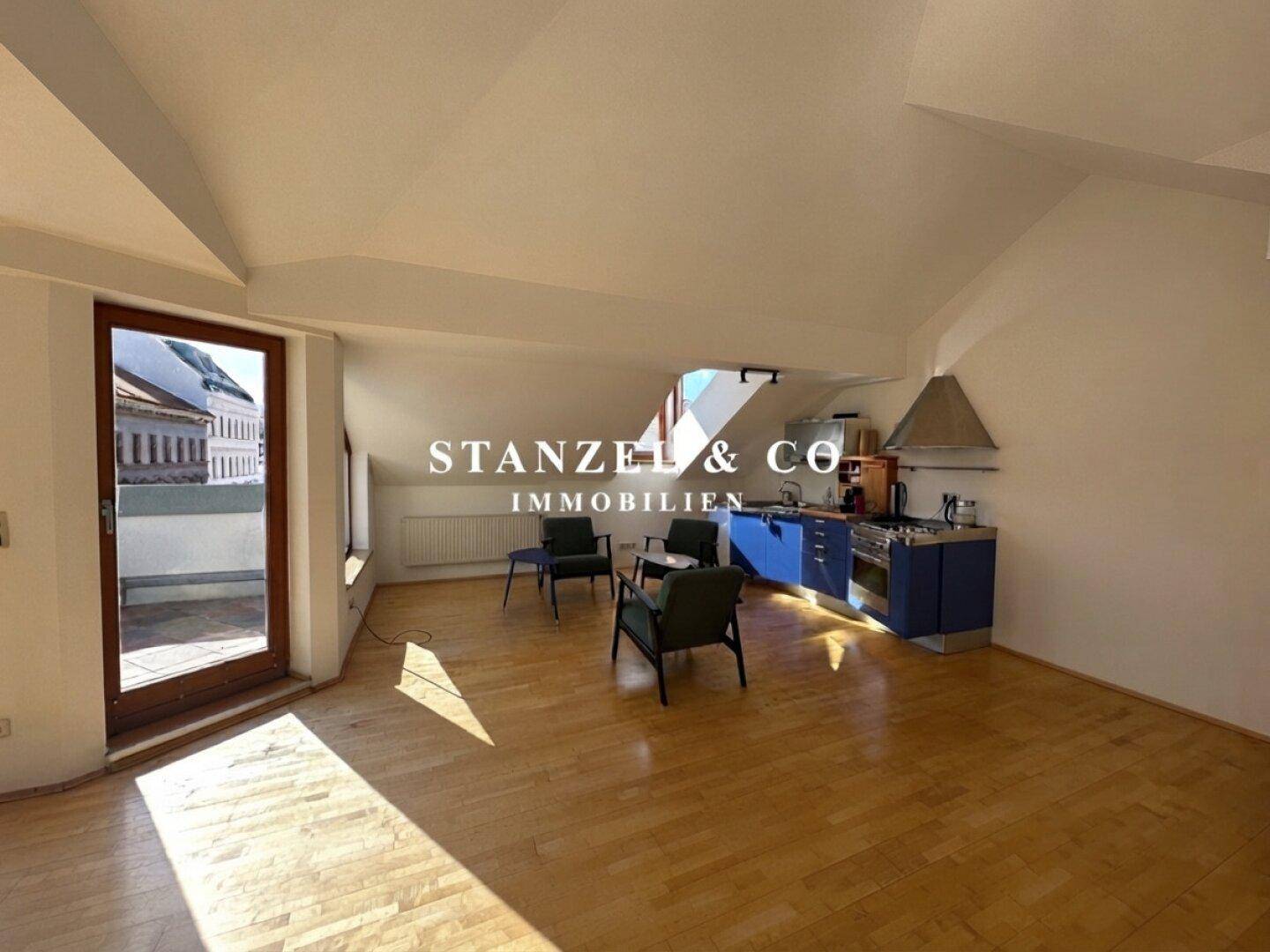 Heller Wohnbereich mit Küchenzeile, Sitzgelegenheiten und Zugang zur Dachterrasse.