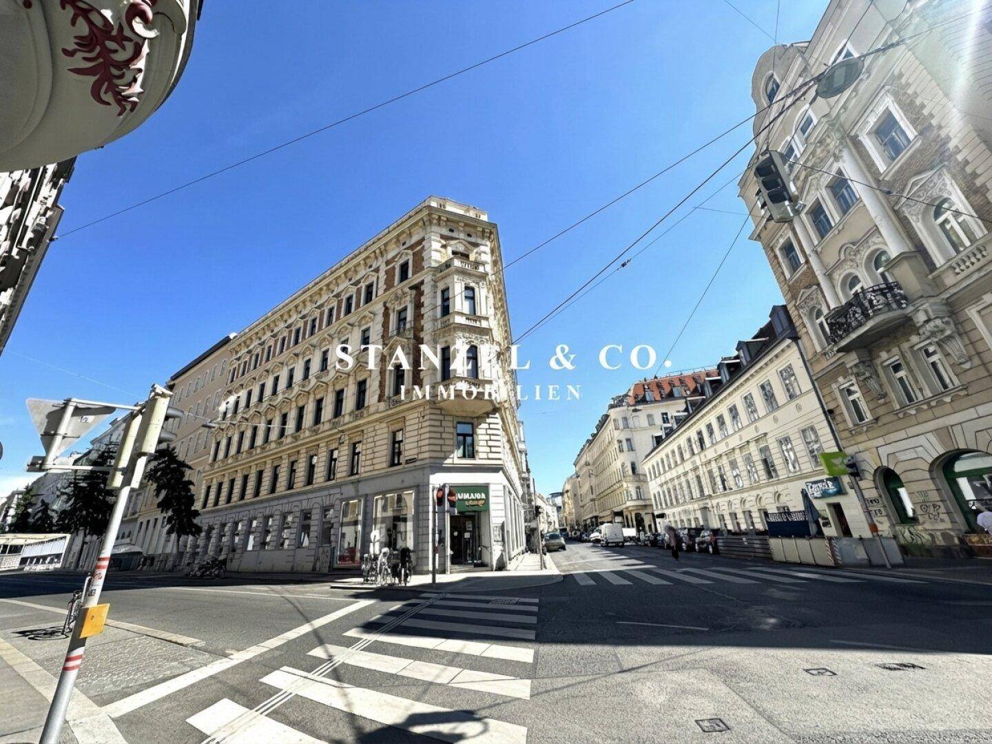 Prächtiges historisches Gebäude an einer städtischen Kreuzung mit eleganter Architektur und sonnigem Wetter.