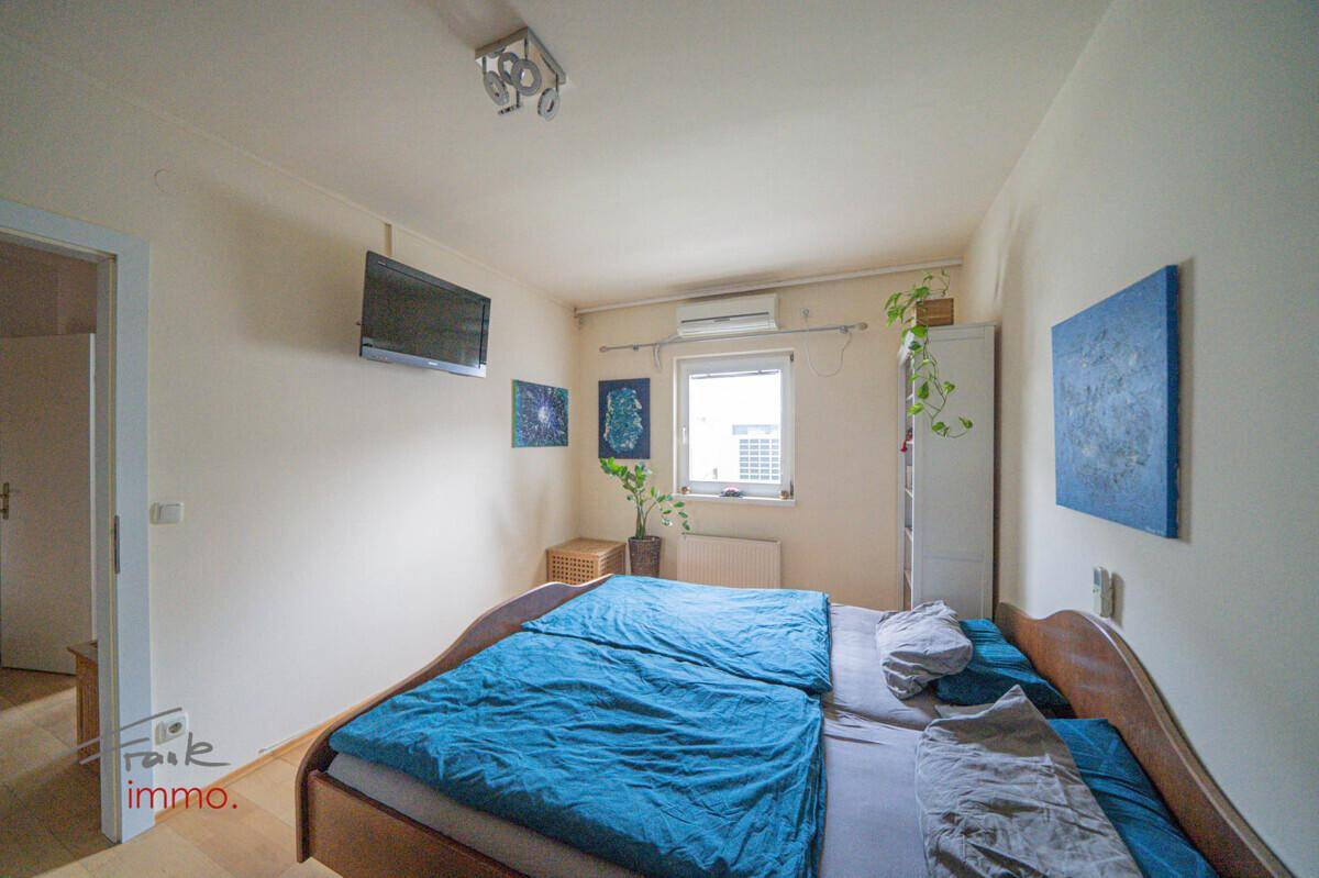 Schlafzimmer mit Doppelbett, Fenster und Klimaanlage für angenehme Temperaturen.
