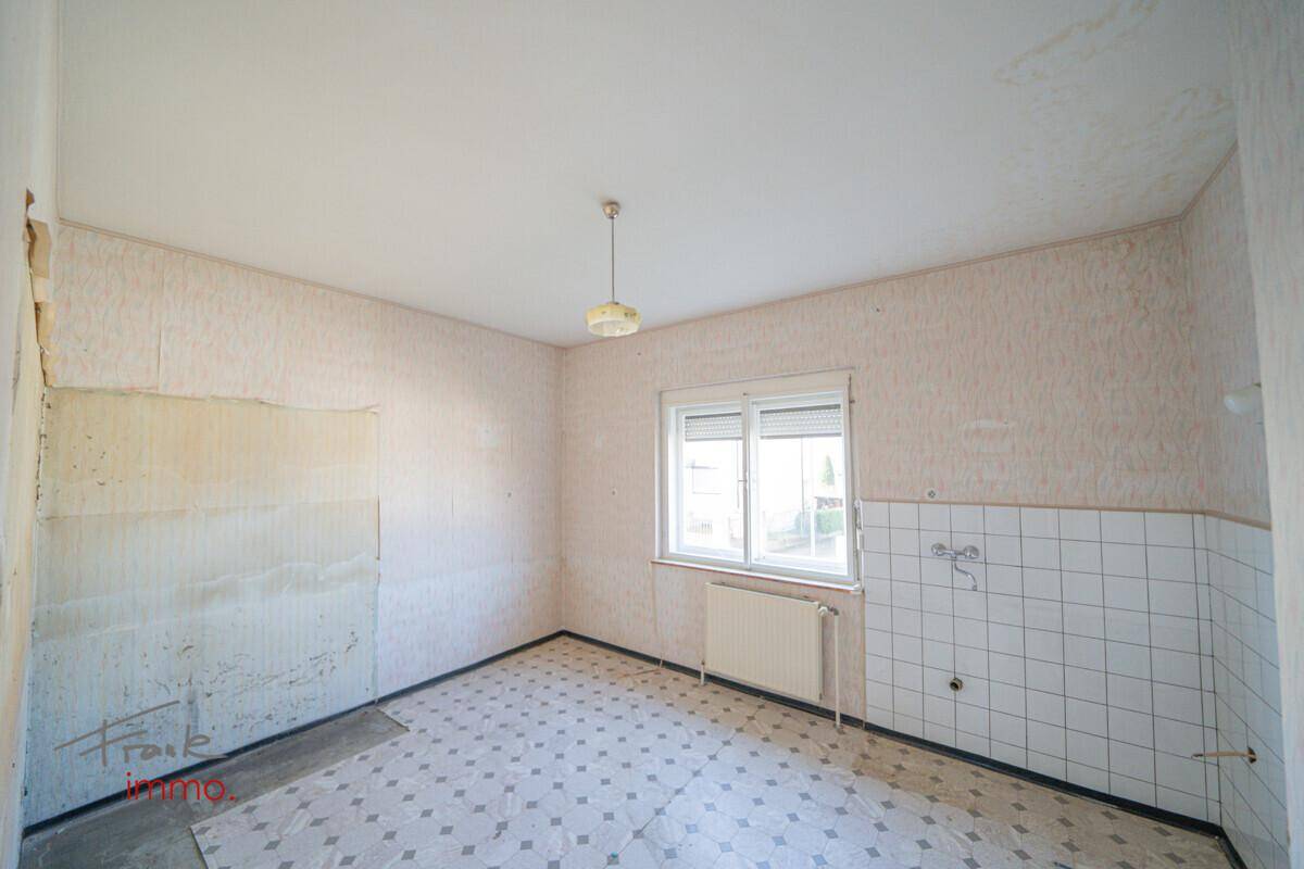 Renovierungsbedürftige Küche mit Fenster und alten Fliesen, ideal für eine moderne Umgestaltung.