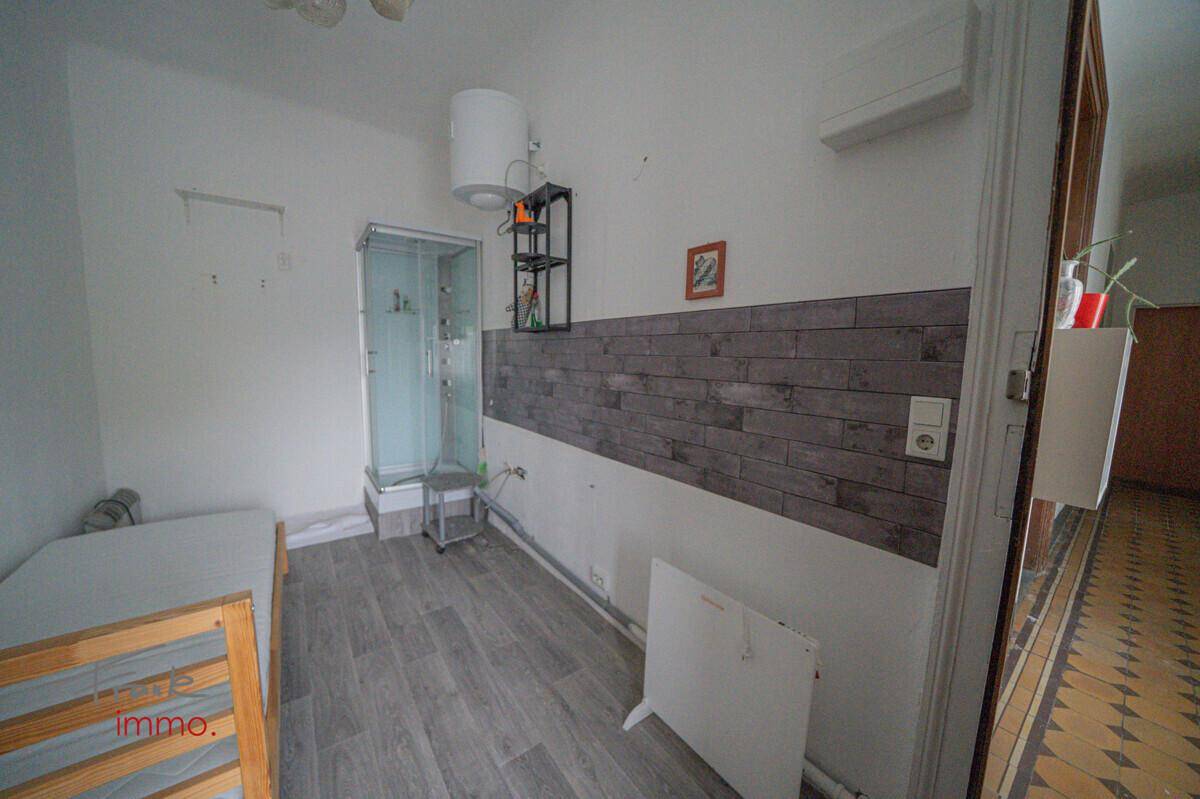 Schlafzimmer mit Bett, Kleiderschrank und einer integrierten Duschkabine.