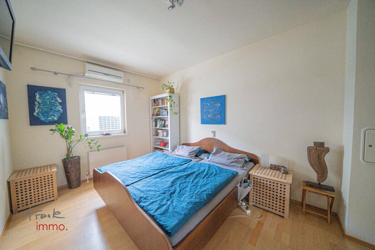 Helles Schlafzimmer mit Doppelbett, Nachttischen und Blick nach draußen durch das Fenster.