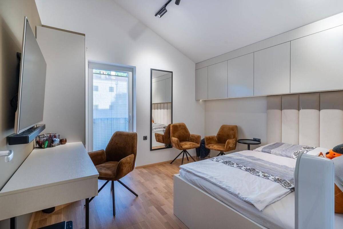 Schlafzimmer mit Holzboden, Schreibtisch und zwei bequemen Sesseln.