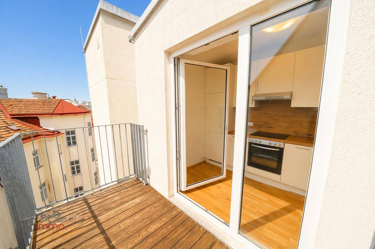 Balkon mit Holzbelag und Blick über die Dächer der Stadt, direkt von der Küche zugänglich.