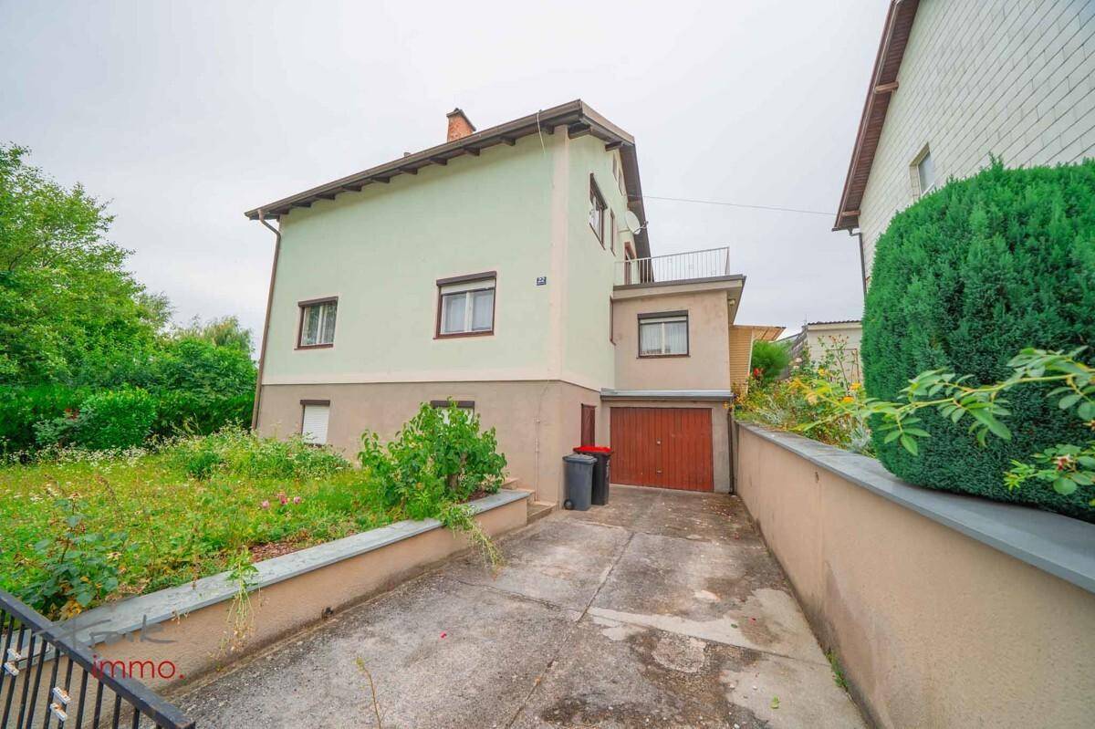 Einfamilienhaus mit Garten, Auffahrt und integrierter Garage an einem bewölkten Tag.