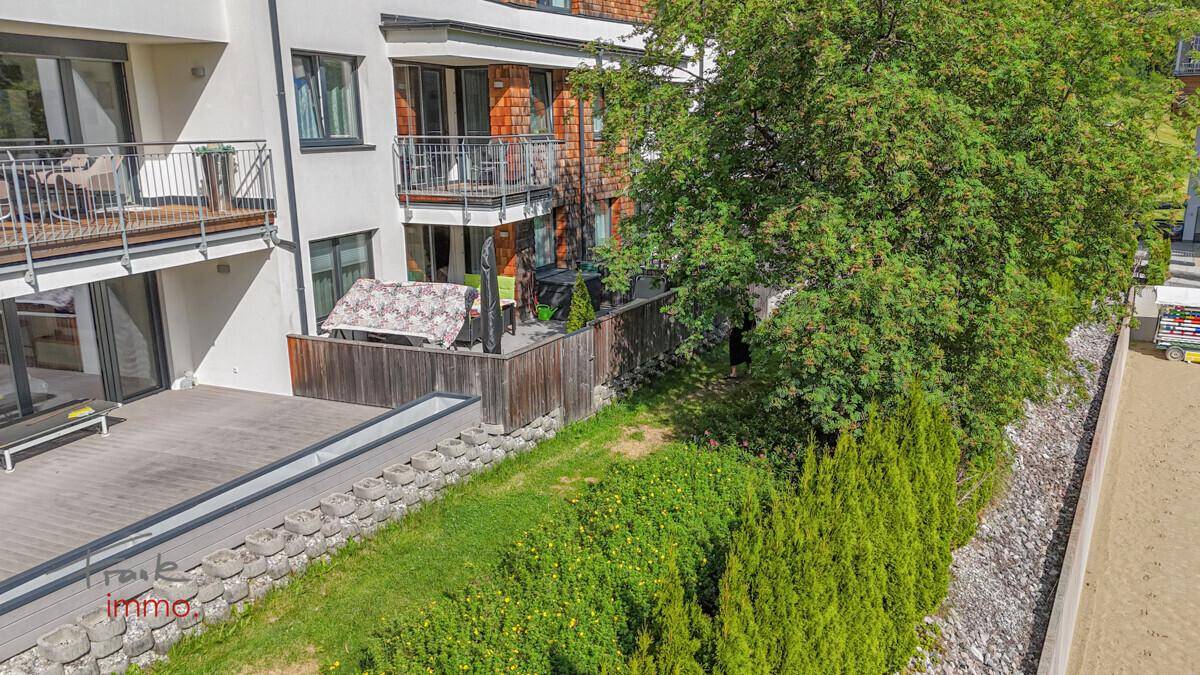 Geräumige Holzterrasse mit Gartenbereich und Blick auf die umliegende grüne Landschaft.