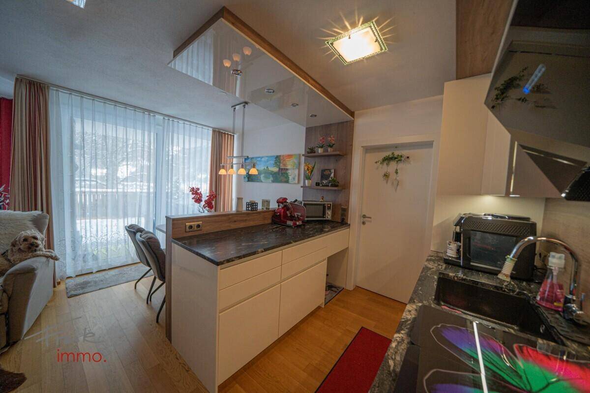 Moderne Küche mit dunkler Arbeitsplatte und Essbereich, offen zum Wohnbereich.