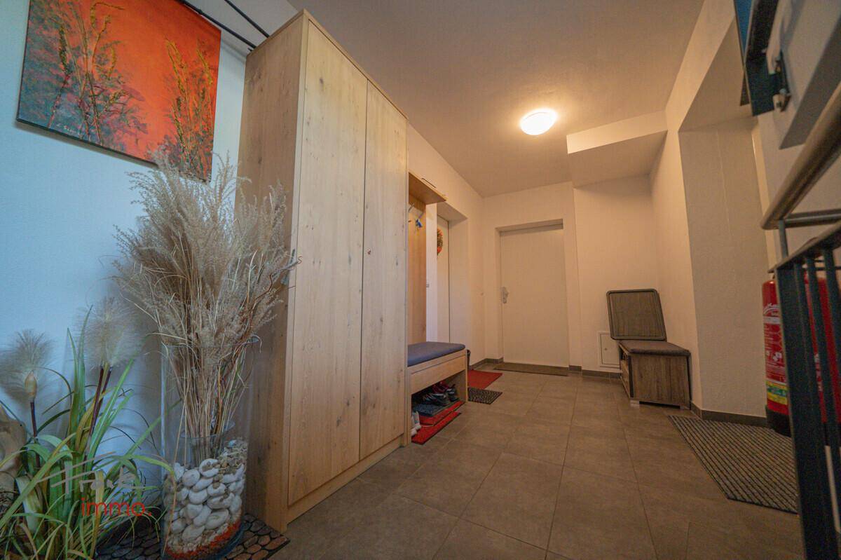 Heller Eingangsbereich mit Holzschrank, Fliesenboden und dekorativen Pflanzen.