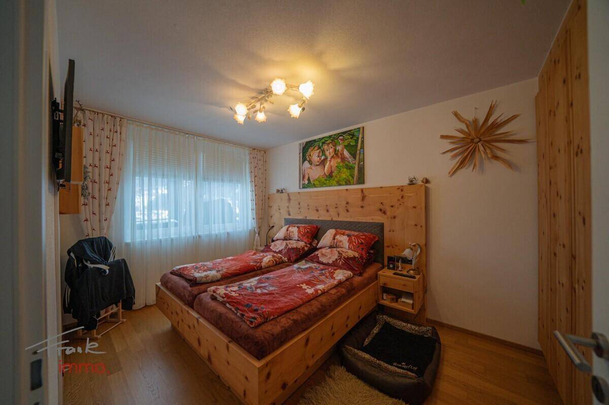 Gemütliches Schlafzimmer mit Holzbett, Holzboden und großem Fenster.