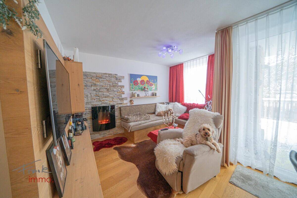 Gemütliches Wohnzimmer mit Kamin, Holzboden und Zugang zur Terrasse.
