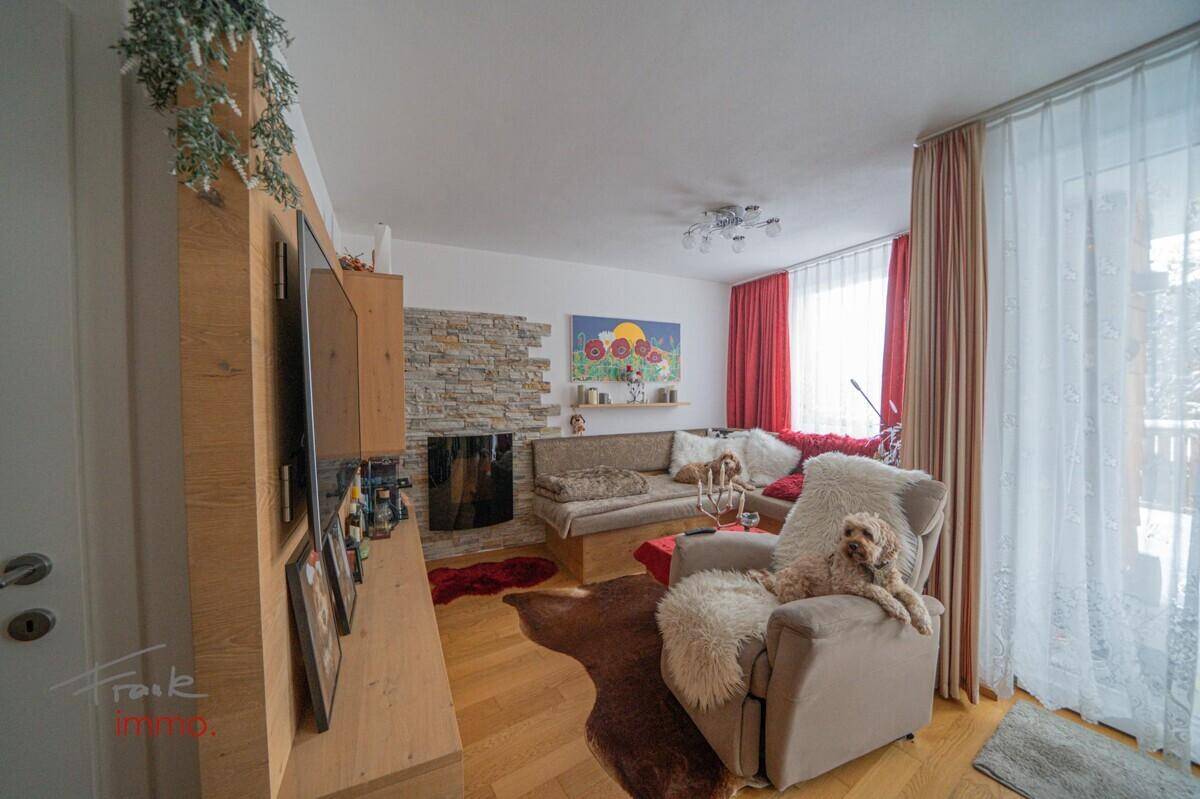 Helles Wohnzimmer mit Kamin, Holzboden und bequemen Sitzgelegenheiten.