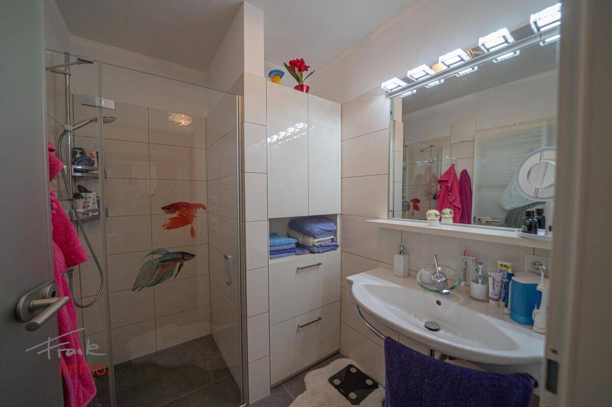 Modernes Badezimmer mit Duschkabine, Waschbecken und Spiegelschrank, gut beleuchtet.