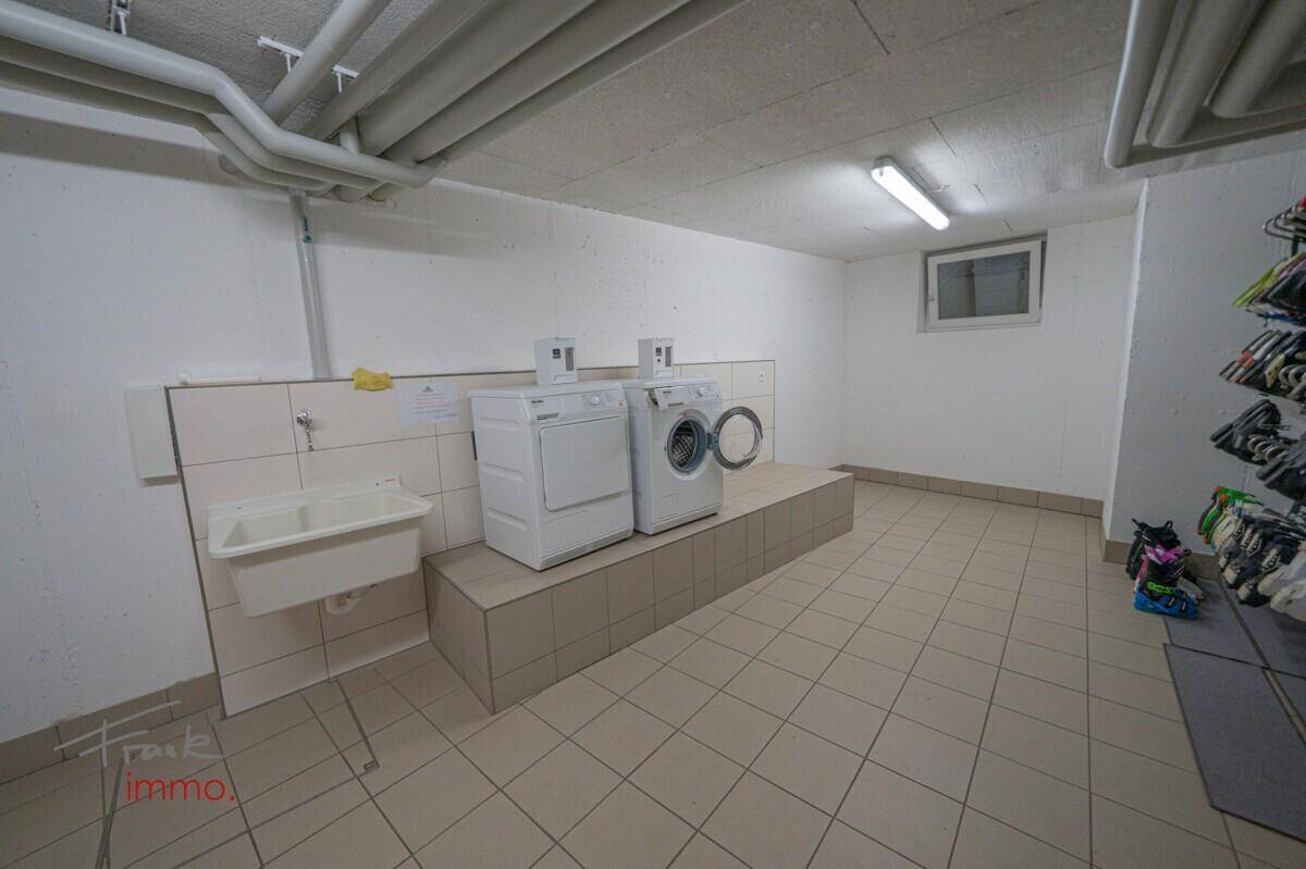 Gemeinschaftlicher Waschraum im Keller mit Waschmaschinen, Trockner und Waschbecken.