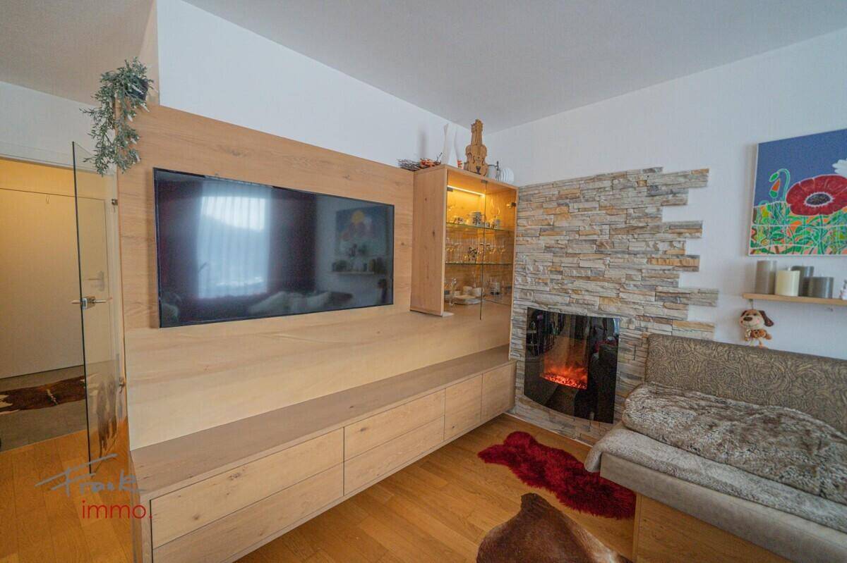 Detailansicht des Wohnzimmers mit Kamin, TV-Möbeln und Holzelementen.