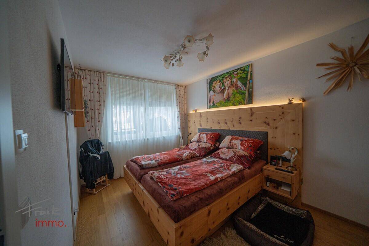 Helles Schlafzimmer mit Holzbett, indirekter Beleuchtung und Holzboden.