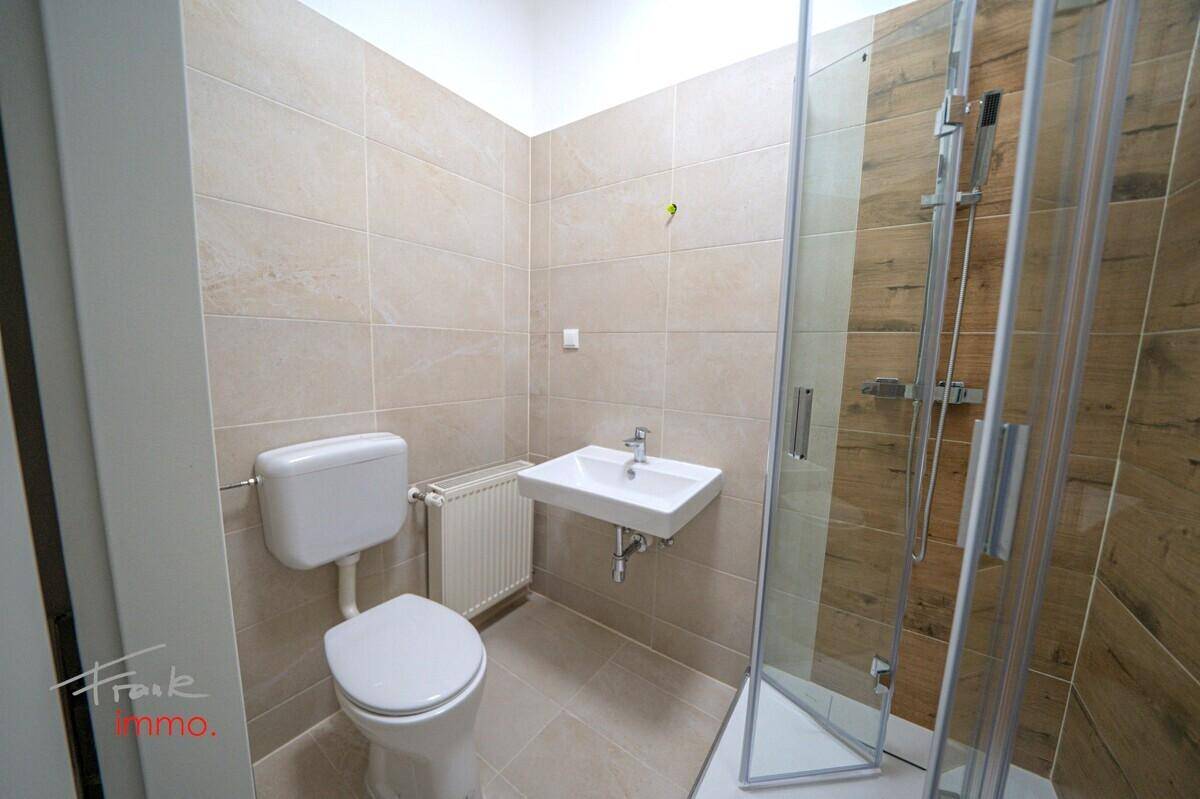 Helles Badezimmer mit WC, Waschbecken und Duschkabine, ausgestattet mit modernen Fliesen.