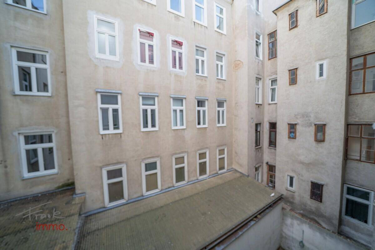 Blick in einen ruhigen Innenhof mit vielen Fenstern und schlichten Fassaden.