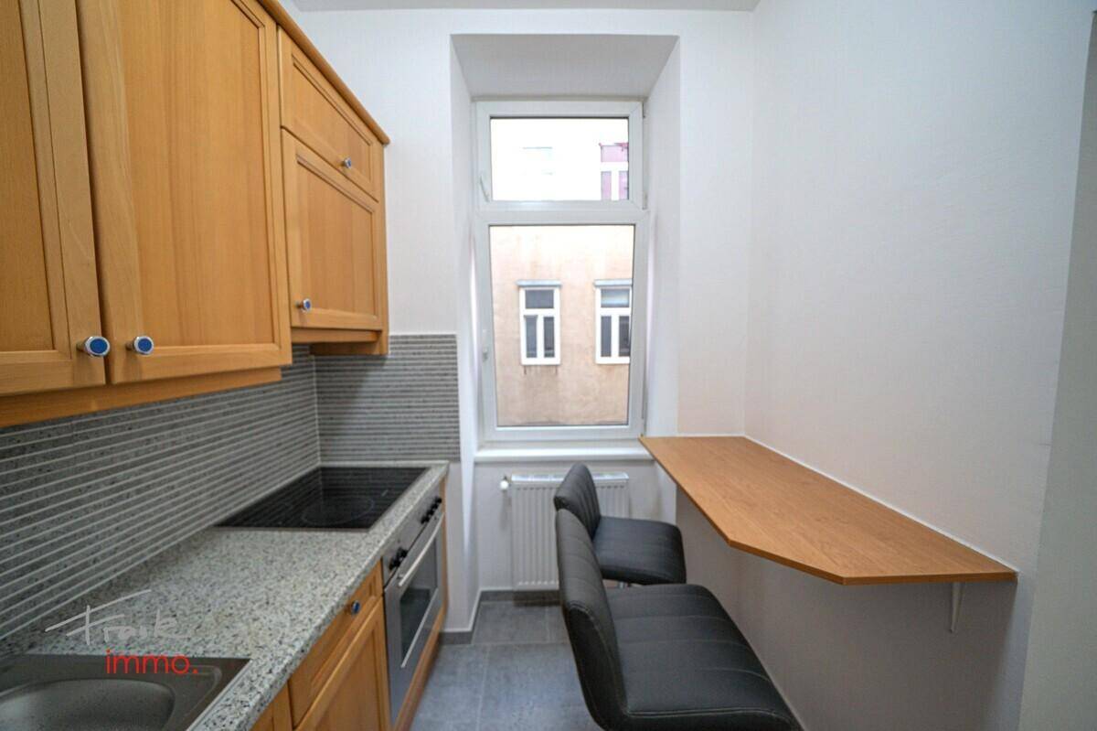 Kleine Küche mit Holzschränken, Granitarbeitsplatte und integriertem Frühstücksbereich am Fenster.