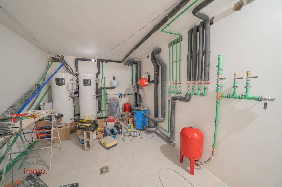 Technikraum mit umfangreichen Rohrleitungen und Warmwasserbereitern, noch im Bau.