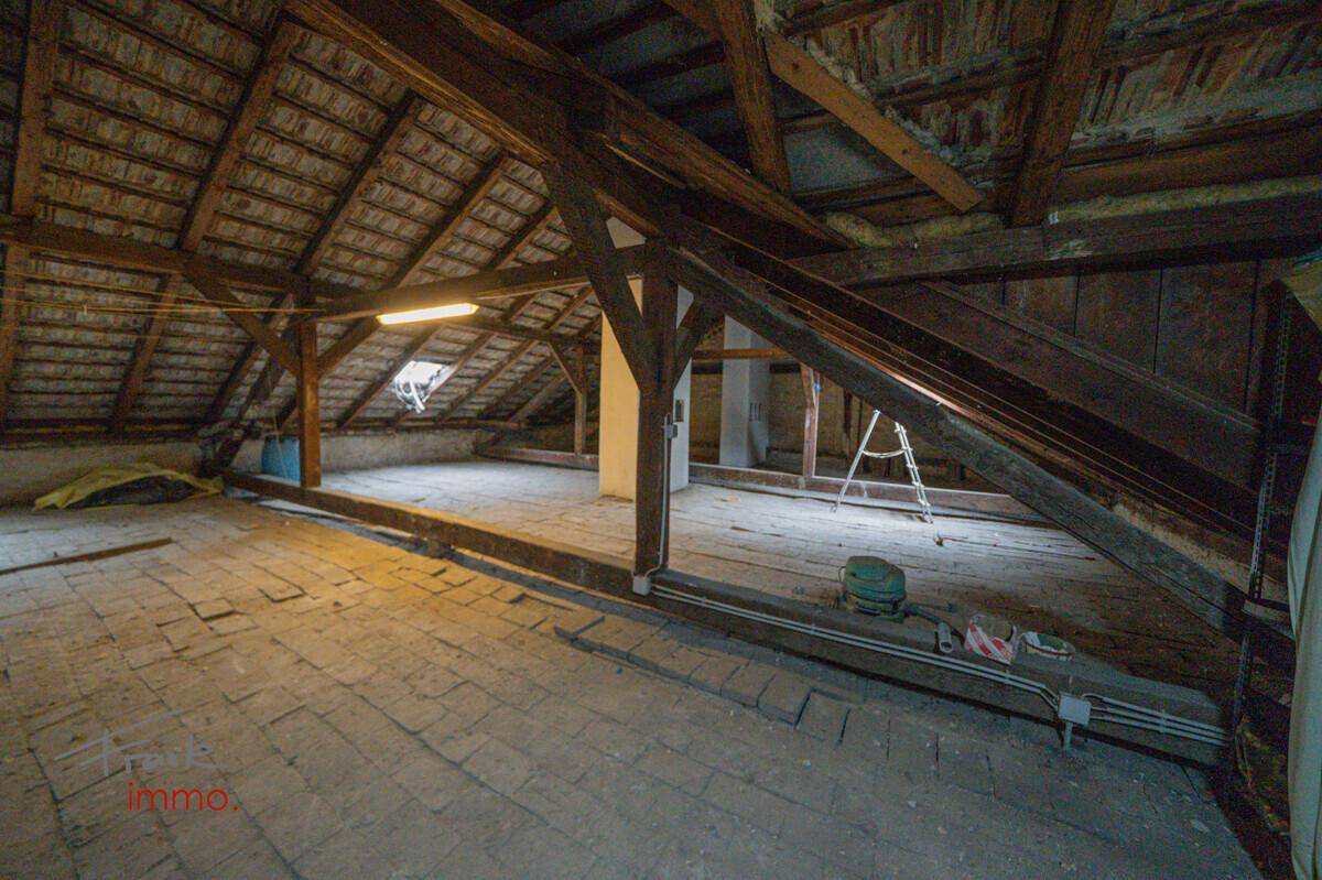 Weitläufiger Dachboden mit Holzbalken und Ziegeln, bietet viel Platz für zukünftige Projekte.