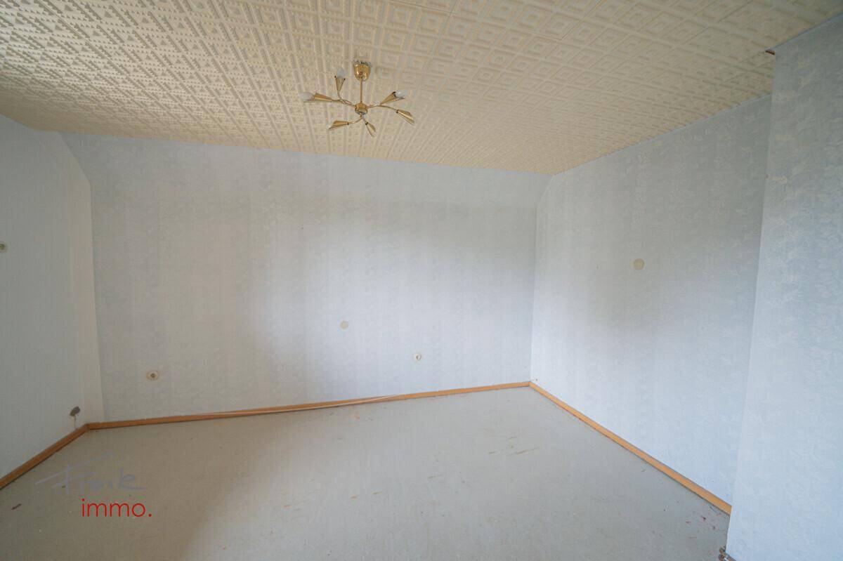 Leeres Zimmer mit Teppichboden und gemusterter Decke, bereit zur individuellen Gestaltung.