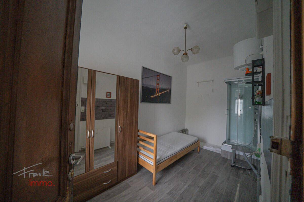Schlafzimmer mit modernem Laminatboden, Kleiderschrank und einer Duschkabine im Raum.