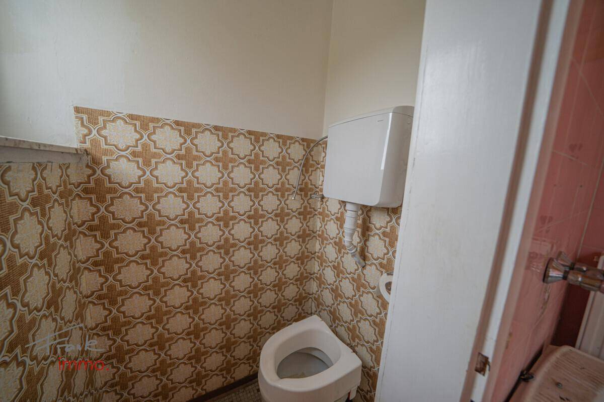 Separate Toilette mit gemusterten Wandfliesen und WC, im Stil der 80er Jahre.