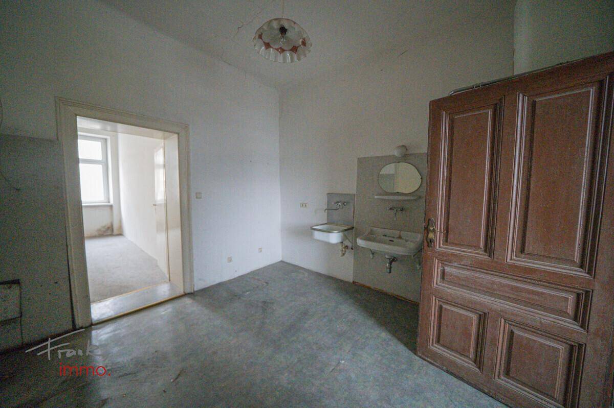Badezimmer in Originalzustand mit zwei Waschbecken und einer Holztür.