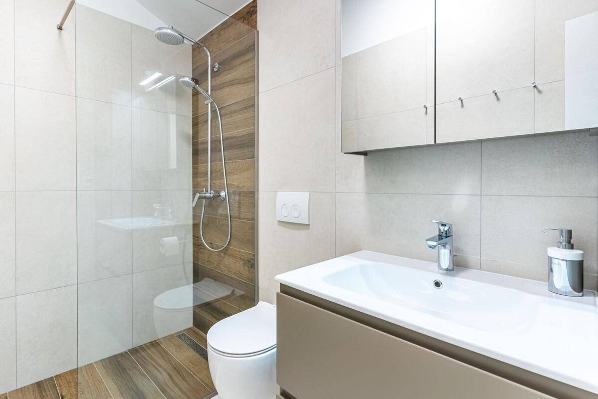 Helles modernes Badezimmer mit begehbarer Dusche, Wand-WC und Waschtisch mit Spiegel.