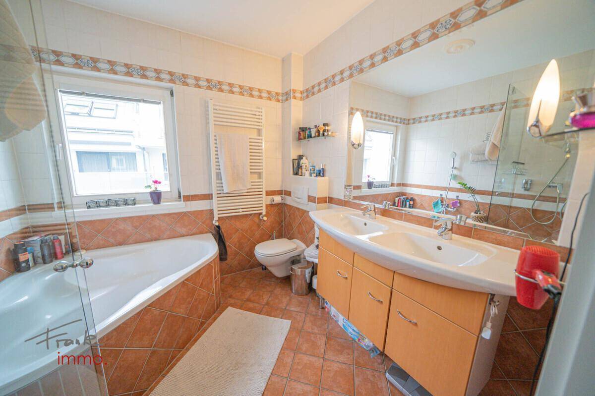 Geräumiges Badezimmer mit Eckbadewanne, Dusche, Doppelwaschbecken und Fenster.