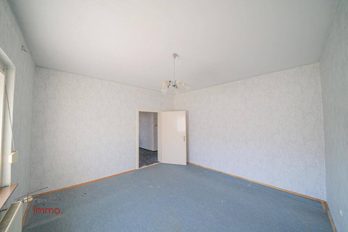 Geräumiges Zimmer mit blauem Teppichboden und weißer Tapete, bereit zur individuellen Neugestaltung.