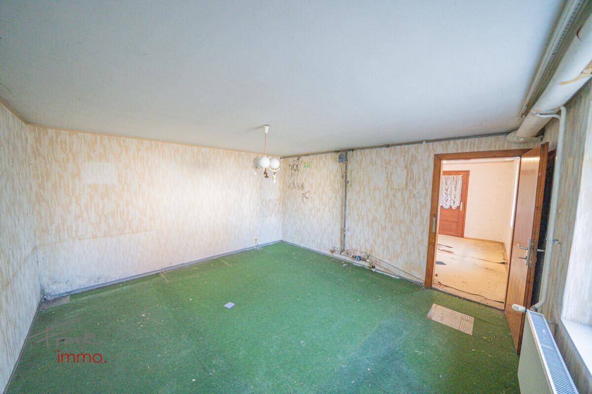 Zimmer mit grünem Teppichboden und Zugang zu einem weiteren Raum, ideal für eine Renovierung.