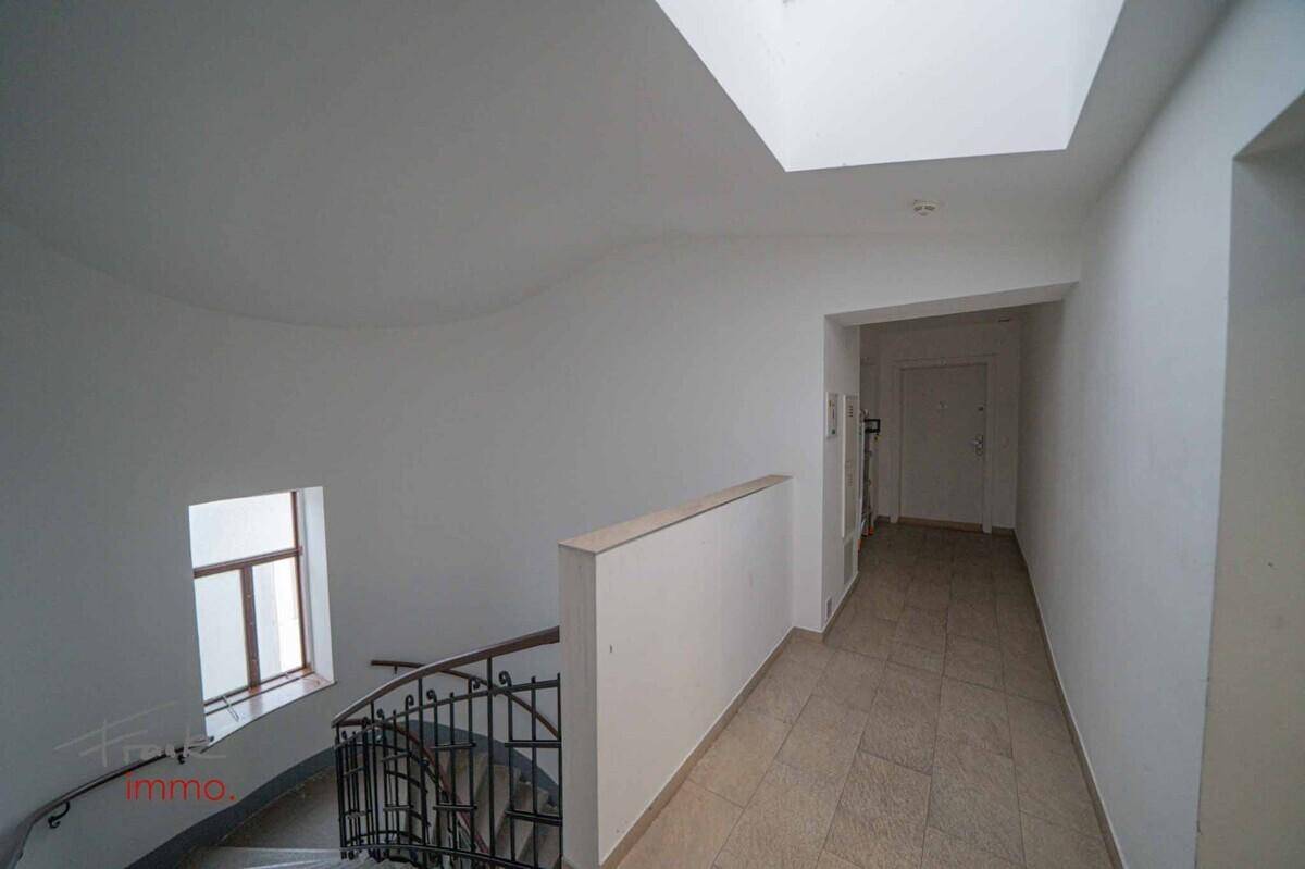 Heller Treppenabsatz mit Fliesenboden, Fenster und Dachfenster, führt zu den Wohnungen.