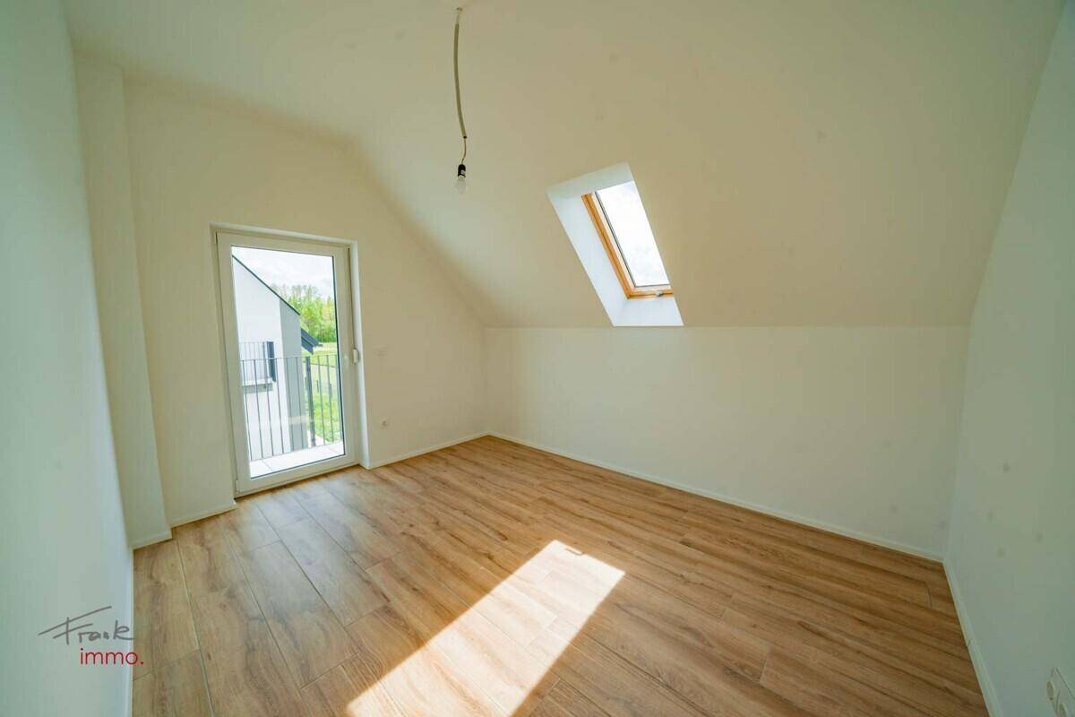 Helles Zimmer mit Dachschräge, Holzoptik-Fliesenboden, Dachfenster und französischem Balkon.