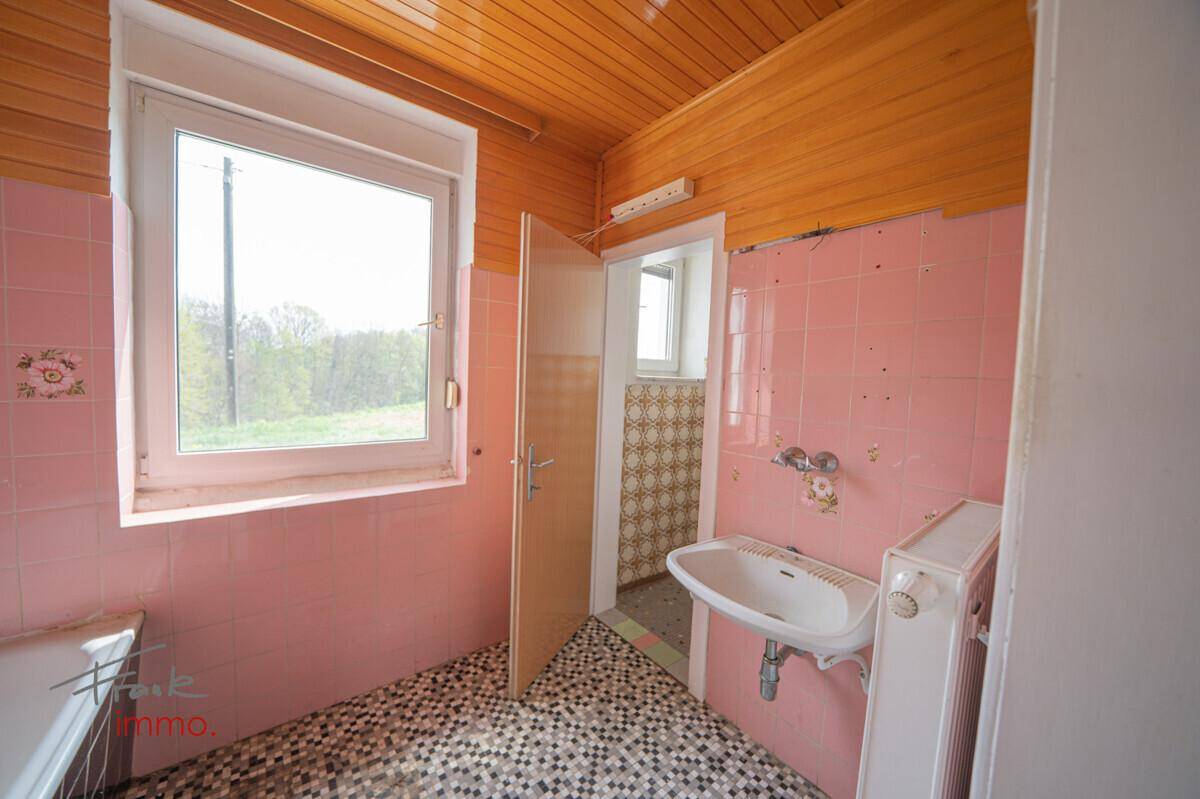 Badezimmer im Stil der 80er Jahre mit rosa Wandfliesen, Waschbecken und Holzdecke.