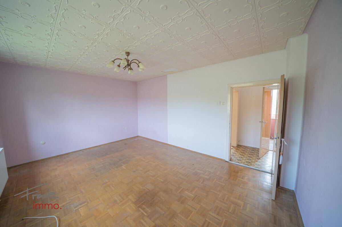 Geräumiges Schlafzimmer mit Parkettboden, rosa Wänden und Zugang zu einem weiteren Raum.