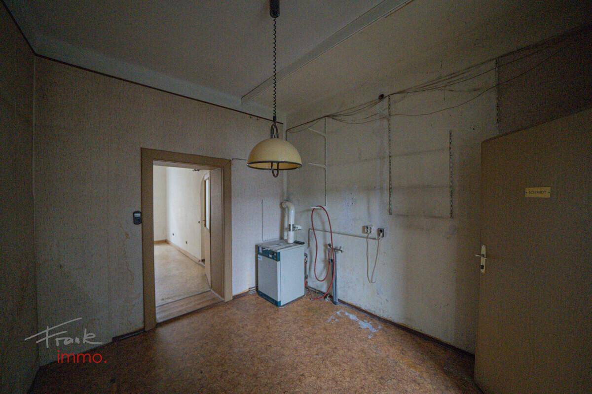Funktionsraum mit Linoleumboden, Warmwasserbereiter und sichtbaren Installationen.