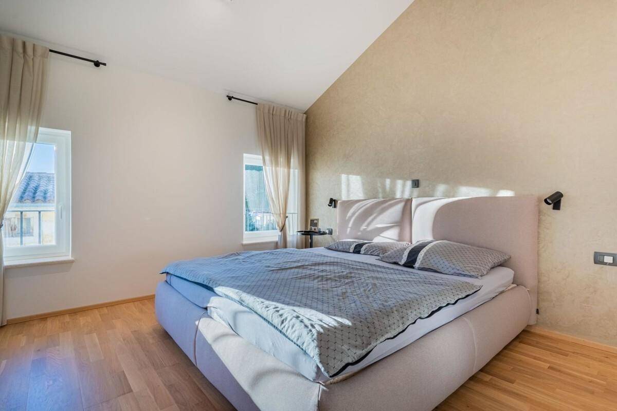 Helles Schlafzimmer mit Doppelbett, Holzboden und strukturierten Wänden.