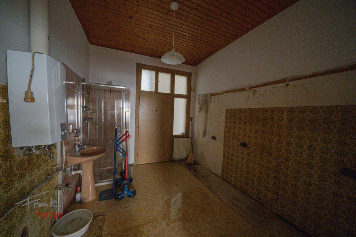 Badezimmer in altem Zustand mit Duschkabine, Waschbecken und Holzpaneeldecke.
